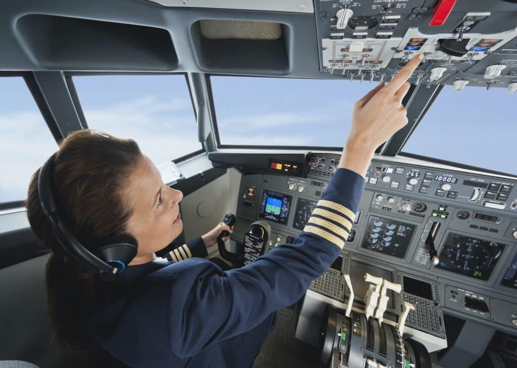 Germany, Bavaria, Munich, Woman flight captain piloting aeroplane from airplane cockpit