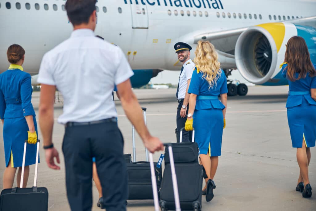 Stewardesses and pilots carrying trolley luggage bags at airport